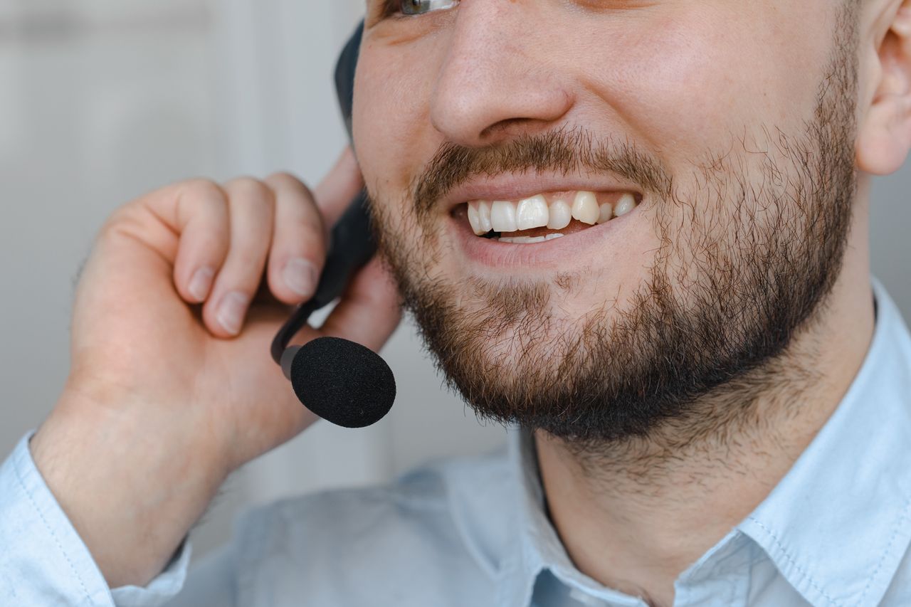 our-story Close-up of a smiling customer support agent wearing a headset microphone.